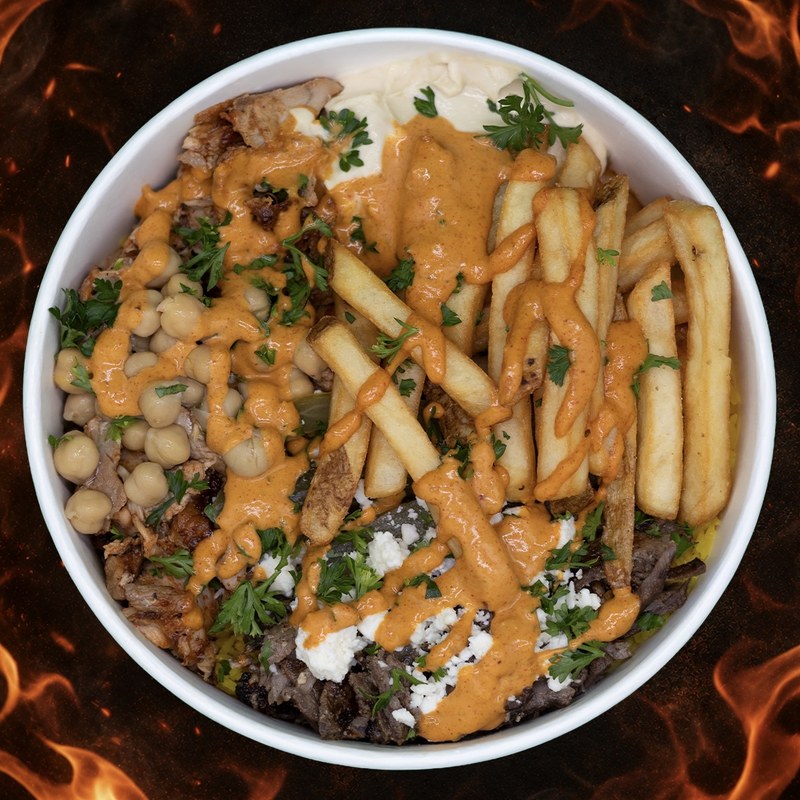 The Nar Grill East Side Bowl, top-down view — steak and chicken shawarma, chickpeas, feta, fries, and spicy Nar X sauce over cilantro rice